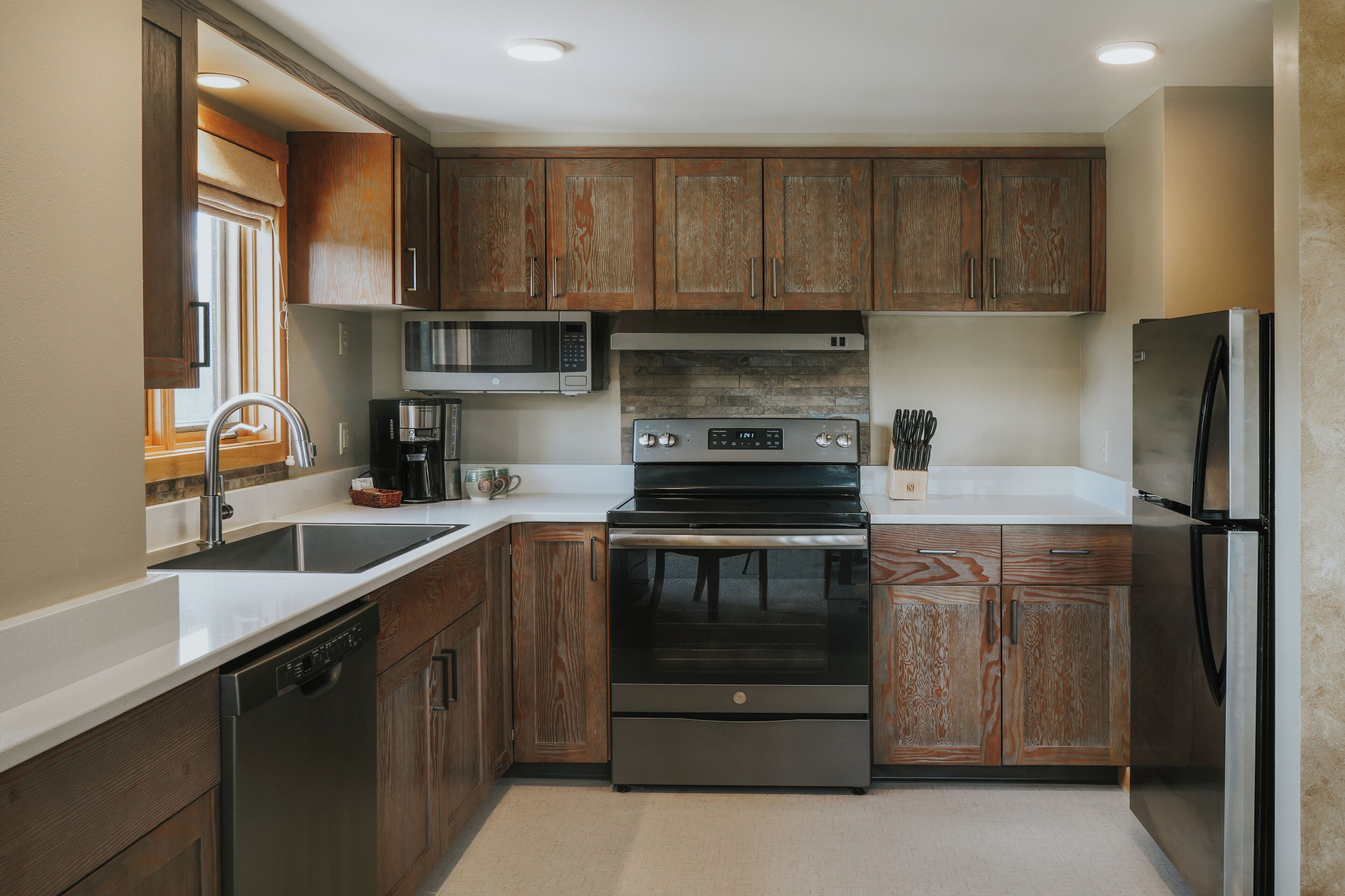 A modern kitchen with wooden cabinets, stainless steel appliances, and a dishwasher.