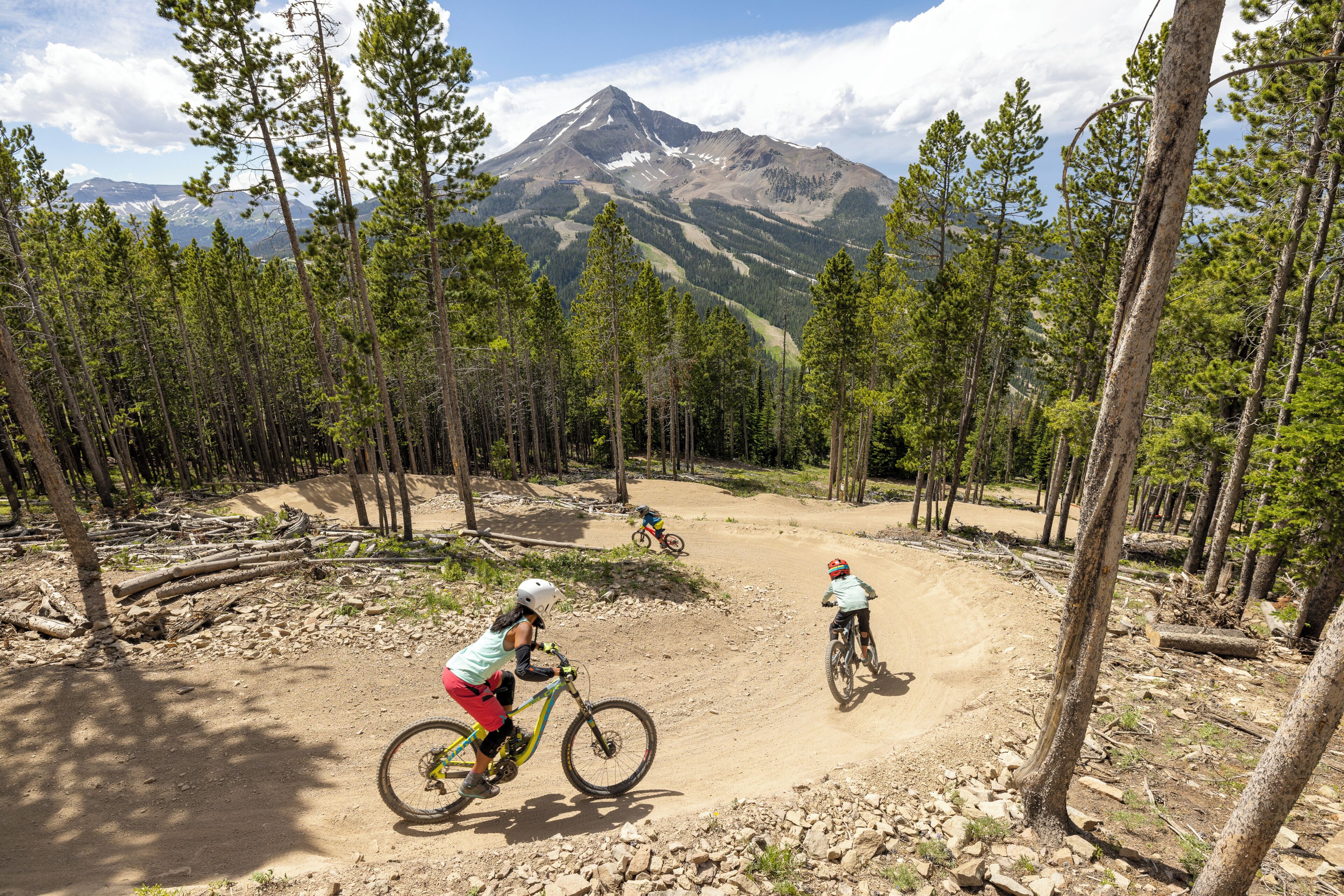 A mountain biking trail surrounded by trees and a mountain in the background.