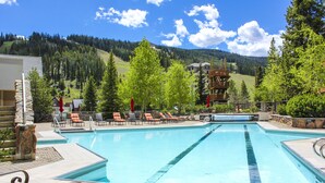 A swimming pool with lounge chairs and a view of a mountainous landscape. - Shoshone Condos at Big Sky Resort (Big Sky)