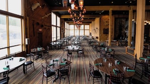 A large dining hall with multiple tables and chairs, wooden beams, and a chandelier. - Shoshone Condos at Big Sky Resort (Big Sky)