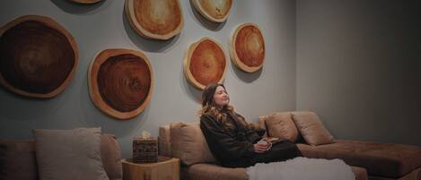 A room with a sofa, a small side table, and a wall with wooden circular decorations.