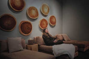 Une piĂšce comprenant un canapĂ©, une petite table dâappoint en bois et un mur ornĂ© de grandes dĂ©corations rondes en bois.