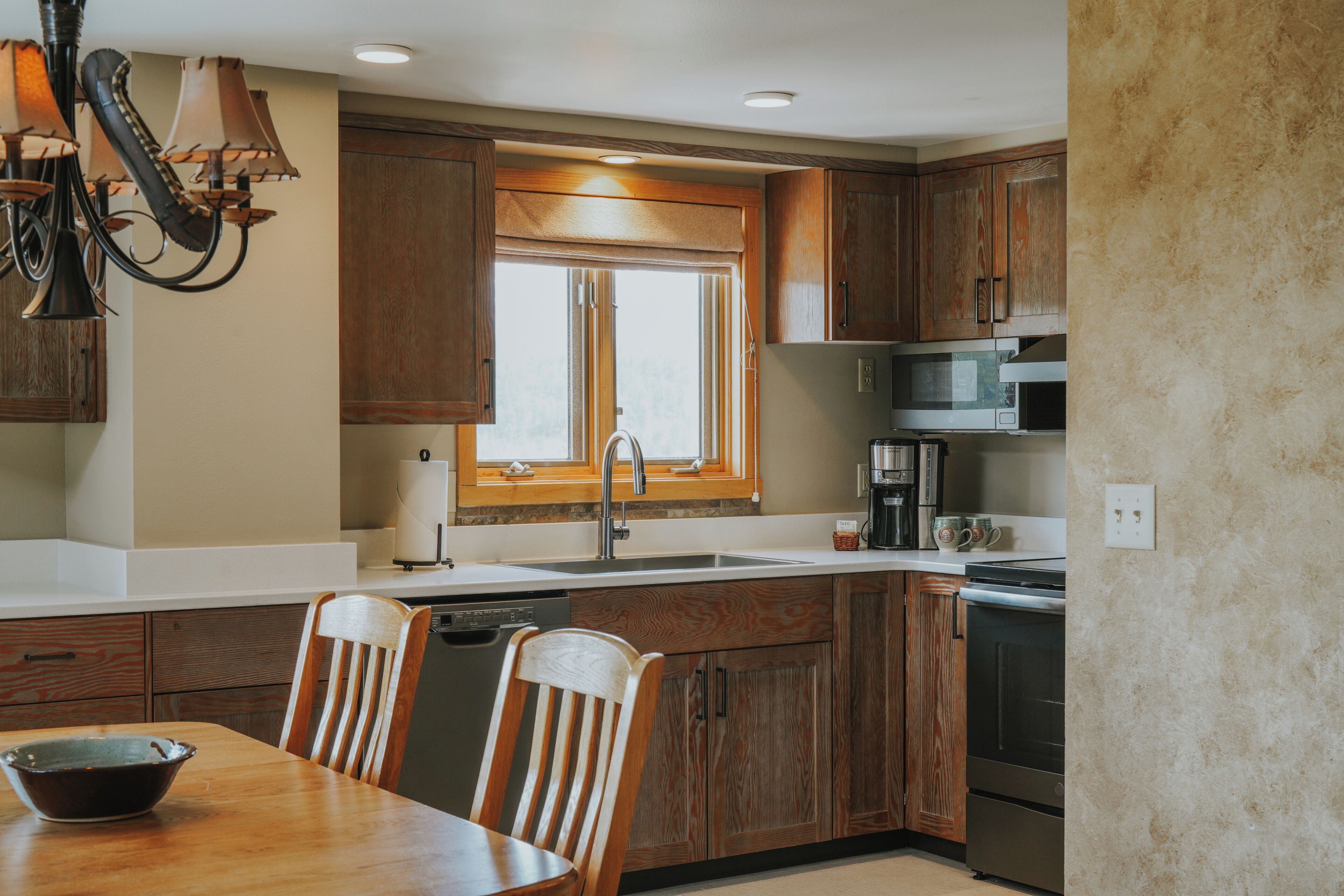 A kitchen with wooden cabinets, a sink, a microwave, and a dishwasher.