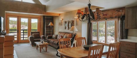 A spacious living area with a dining table, chairs, a sofa, and a chandelier.
