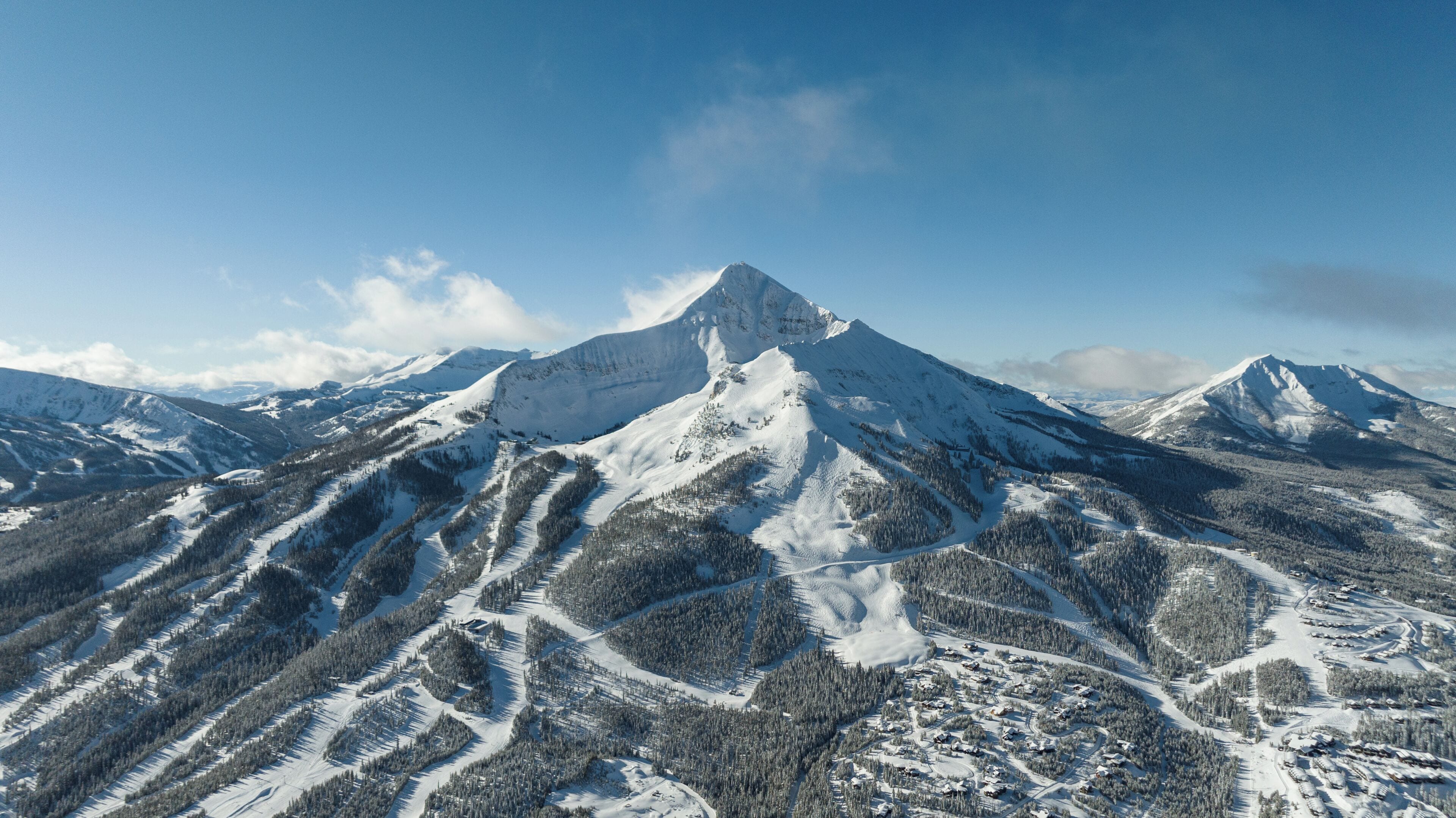 A snow-covered mountain with a ski resort in the foreground.