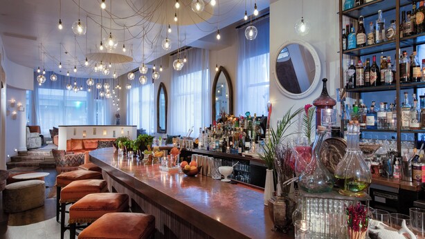 A bar area with a long counter, multiple stools, and a variety of bottles and glasses on shelves. - Loft 523 New Orleans (New Orleans)