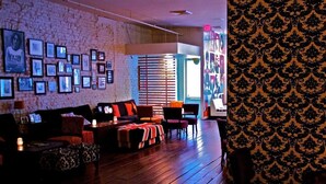 A cozy living room with a brick wall adorned with framed pictures, a wooden floor, and a patterned wallpaper on the right. - Loft 523 New Orleans (New Orleans)