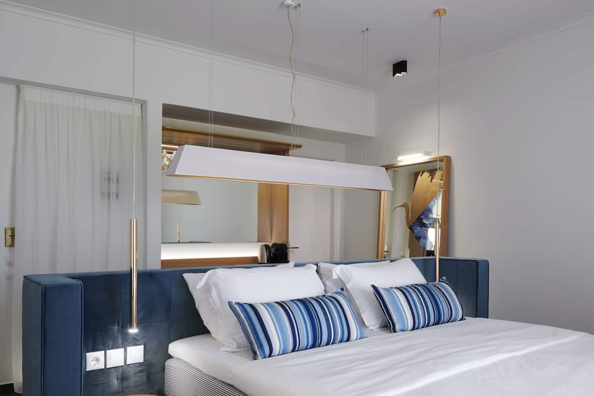 A modern hotel room with a large bed, a bedside table, a mirror, and a wardrobe.