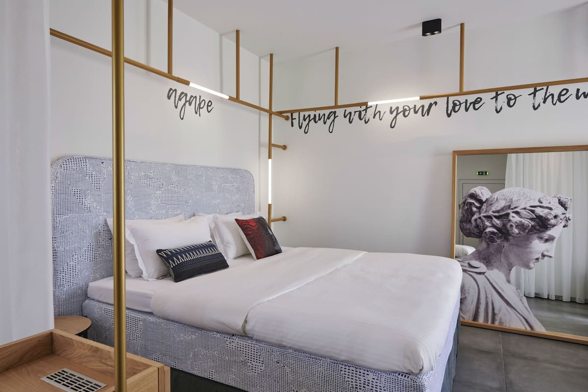 A modern bedroom with a bed, a mirror, and motivational wall art.