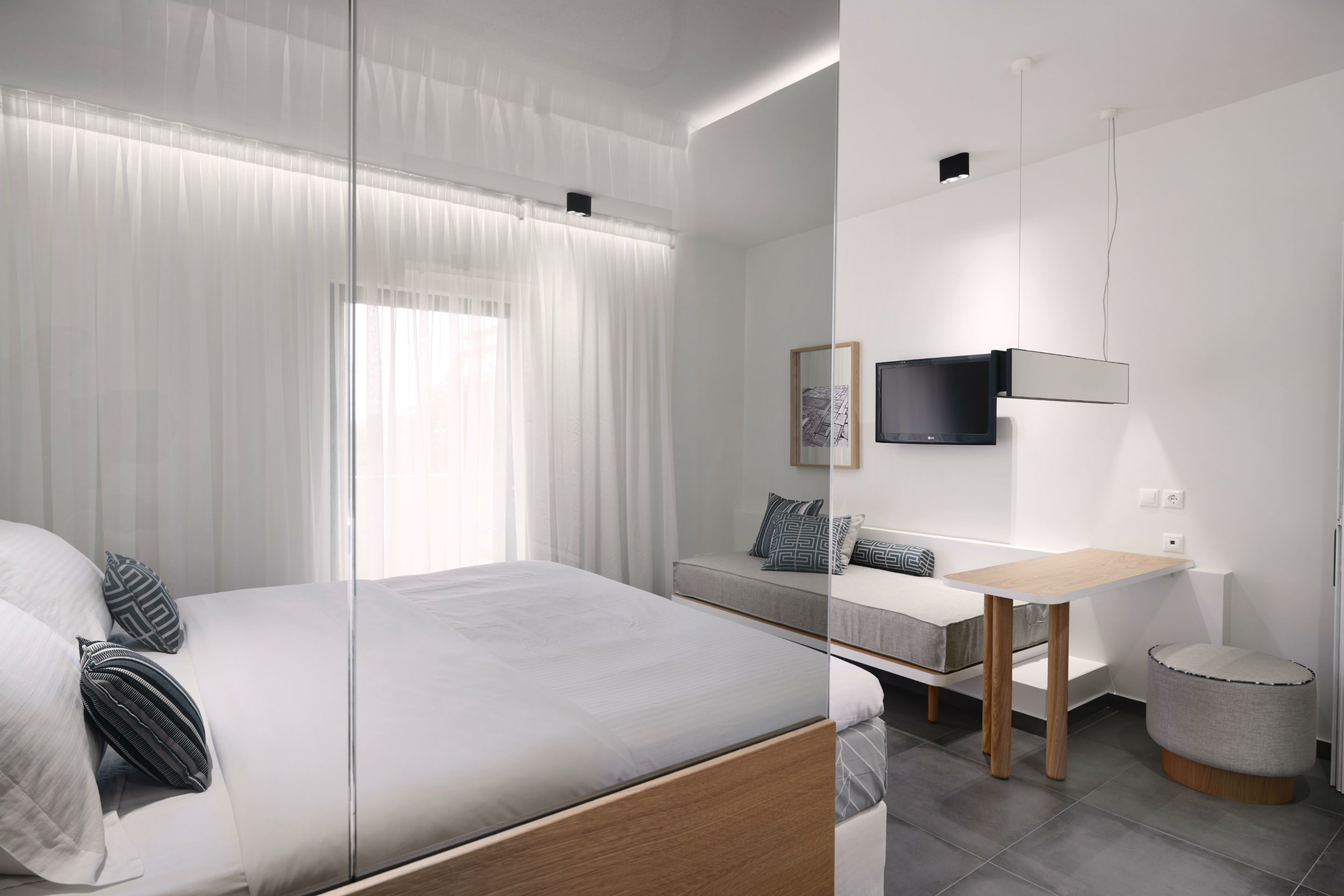 A modern bedroom with a bed, bedside table, and a TV mounted on the wall.