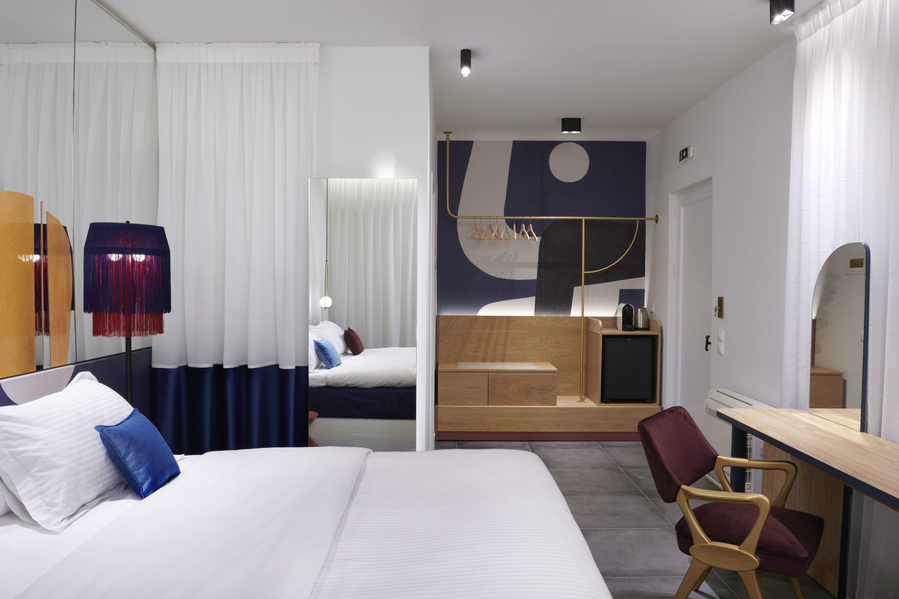 Una habitación de hotel moderna con una cama grande, un escritorio, una silla, un armario y un baño.