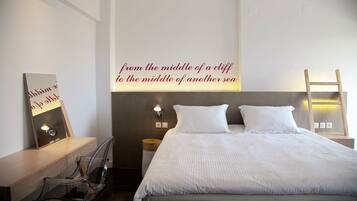 A bedroom with a bed, a bedside table, a chair, a wall-mounted ladder, and a motivational quote on the wall.