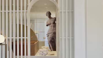 A modern bathroom with a freestanding bathtub, a marble countertop, and a statue.