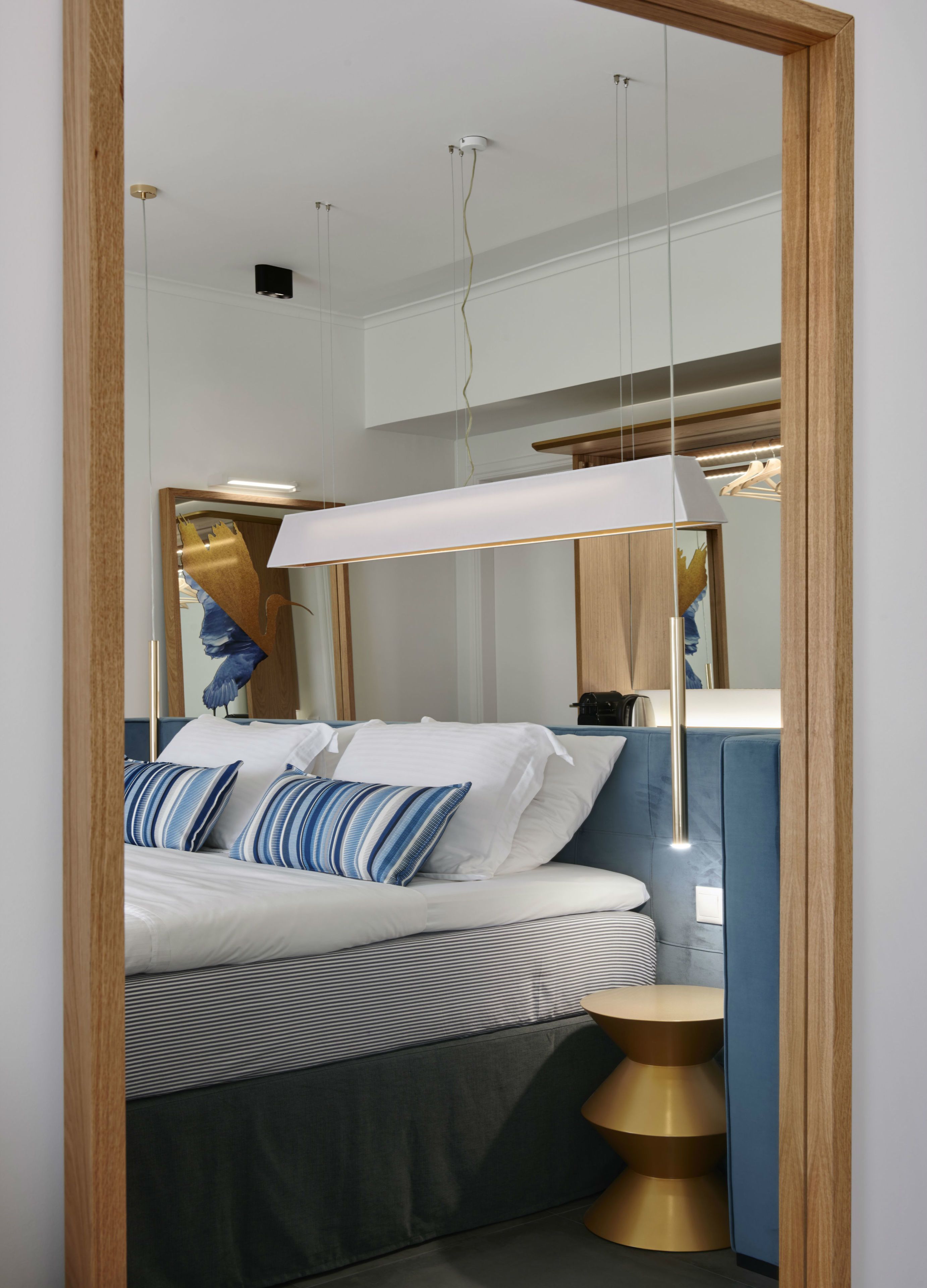 A modern bedroom with a bed, bedside table, and a mirror.