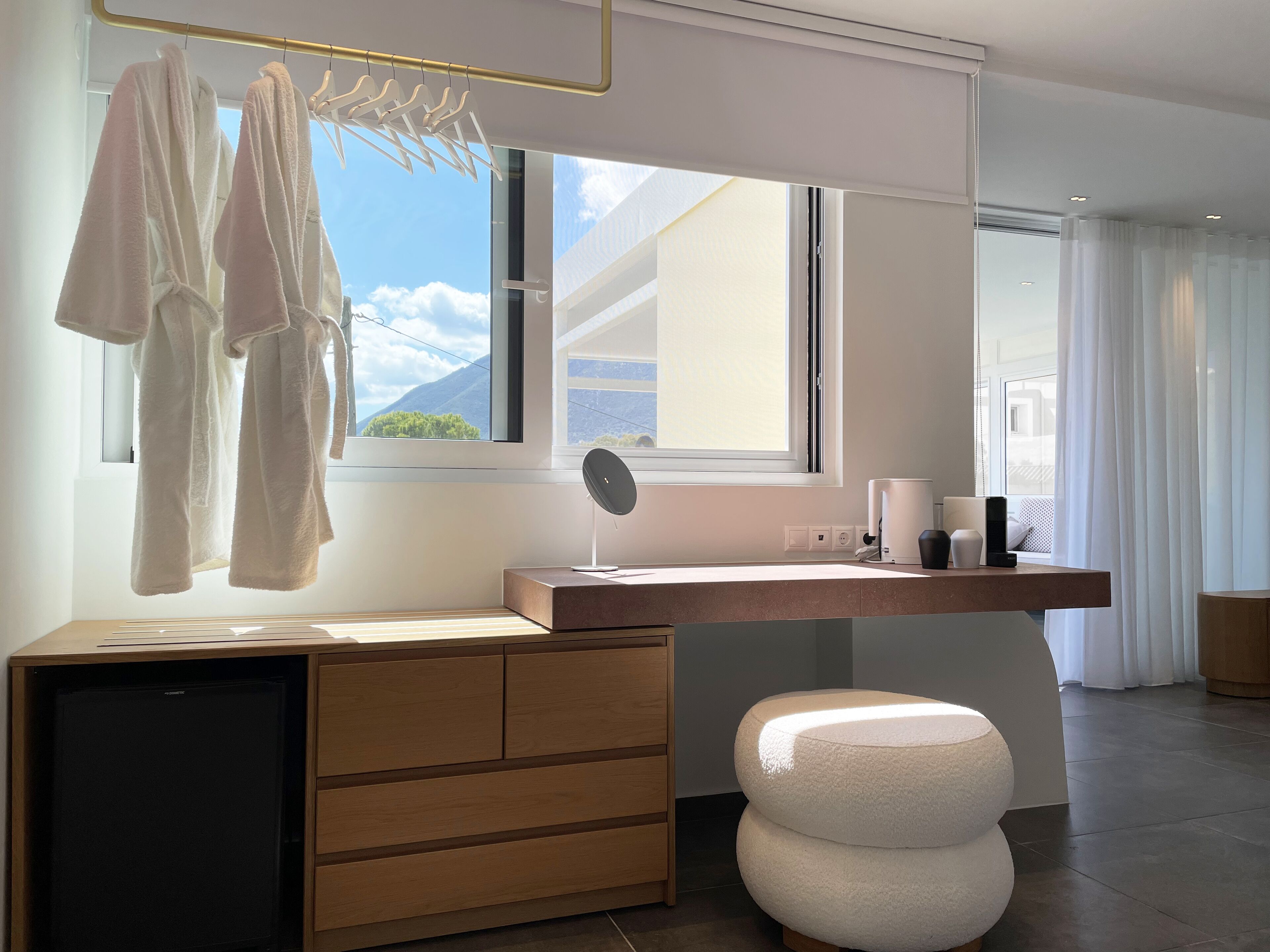A modern bathroom with a wooden vanity, a large mirror, and a view of the mountains through the window.