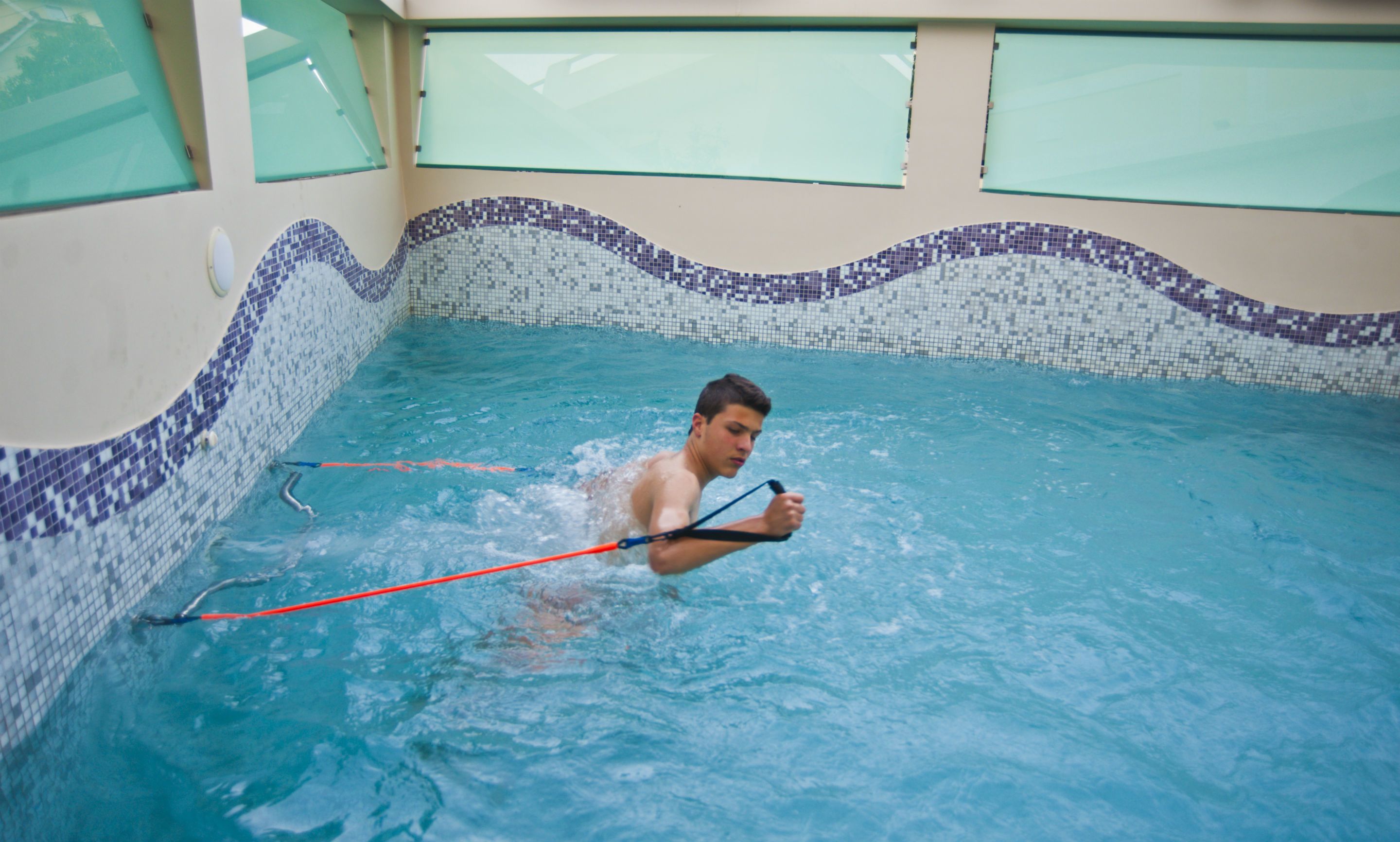 Un hombre en una piscina usando una banda de resistencia.