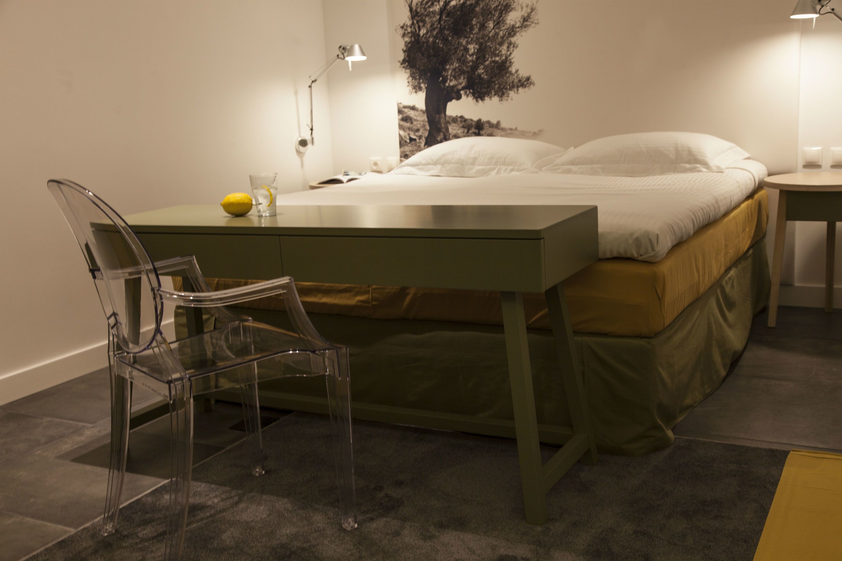A room with a bed, a desk, a chair, and a lamp.