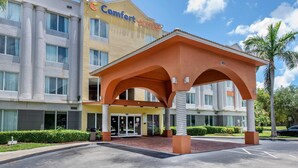 Un hotel con un letrero de 'Comfort Suites', una entrada cubierta y un estacionamiento.