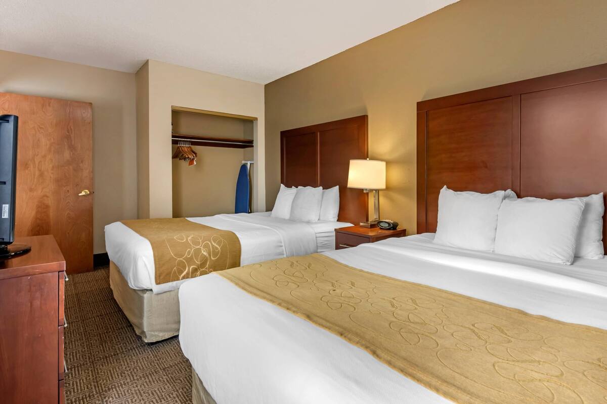 Habitación de hotel con dos camas, un escritorio, un televisor y un armario.
