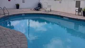 A swimming pool with lounge chairs and a small staircase.