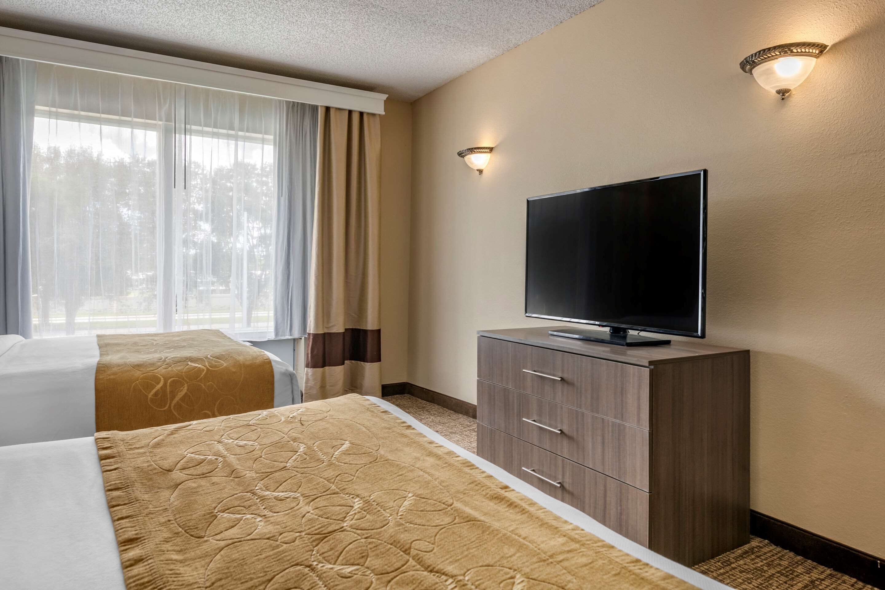 A hotel room with two beds, a TV on a wooden cabinet, and a window with curtains.