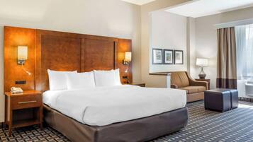 A hotel room with a large bed, a sofa, a small table, and a lamp.