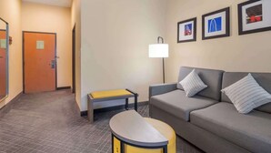 A hotel lobby with a sofa, a bench, a lamp, and framed pictures on the wall.