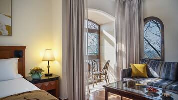 Habitación de hotel con cama, sofá, mesa de comedor y vistas al exterior.