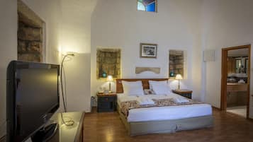 Een hotelkamer met een bed, een televisie, een stenen muur en een klein raam.