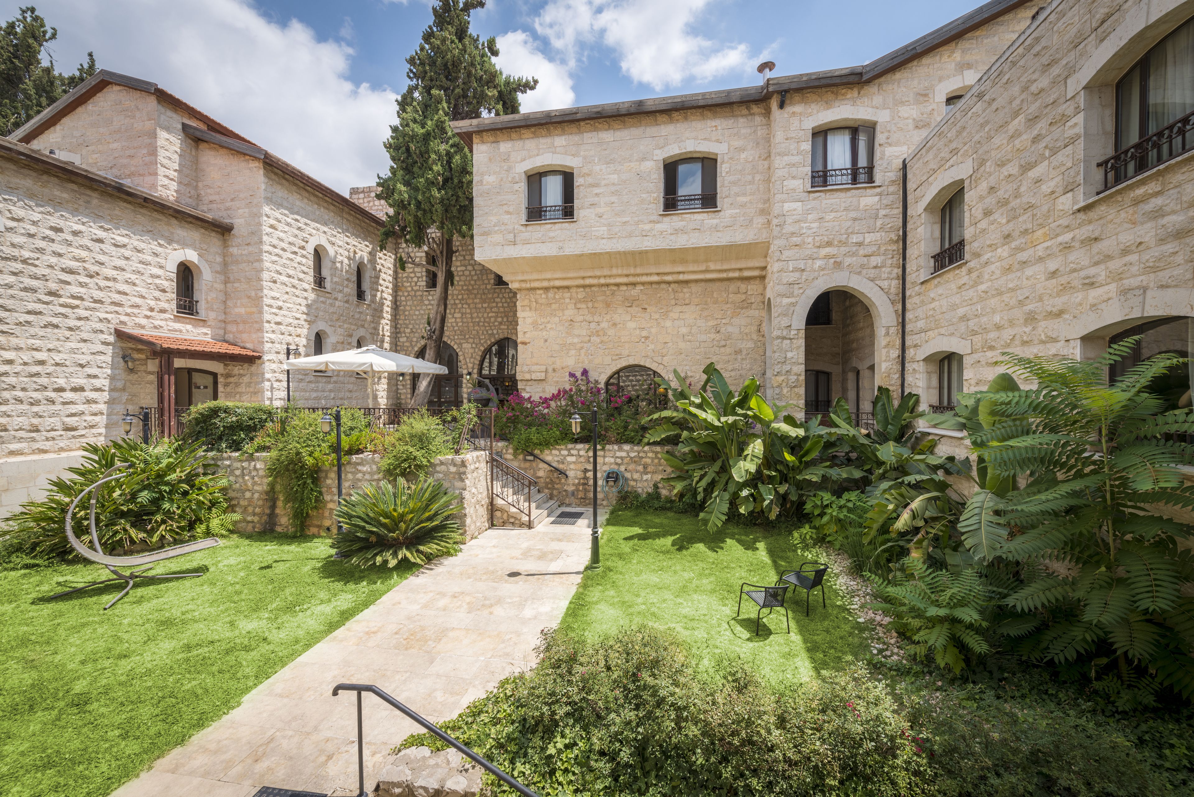 A courtyard with stone buildings, a grassy area, and a metal sculpture.
