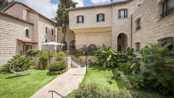 A courtyard with stone buildings, a grassy area, and a metal sculpture.