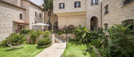 A courtyard with stone buildings, a grassy area, and a metal sculpture.