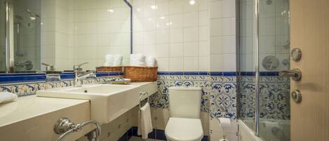 Un baño con bañera, inodoro, lavamanos y cabina de ducha de vidrio.