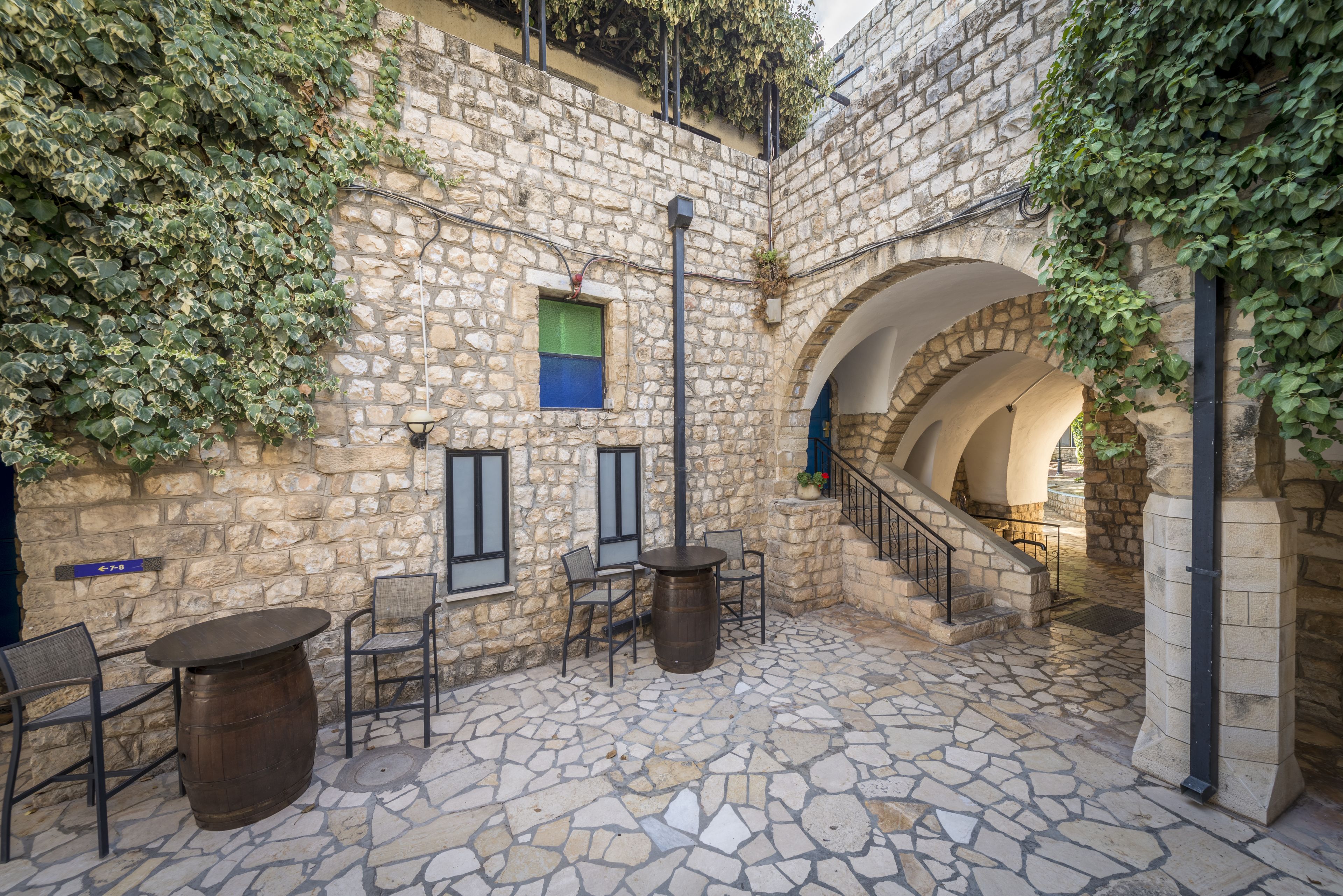 An outdoor patio with stone flooring, a wooden barrel table, and chairs.