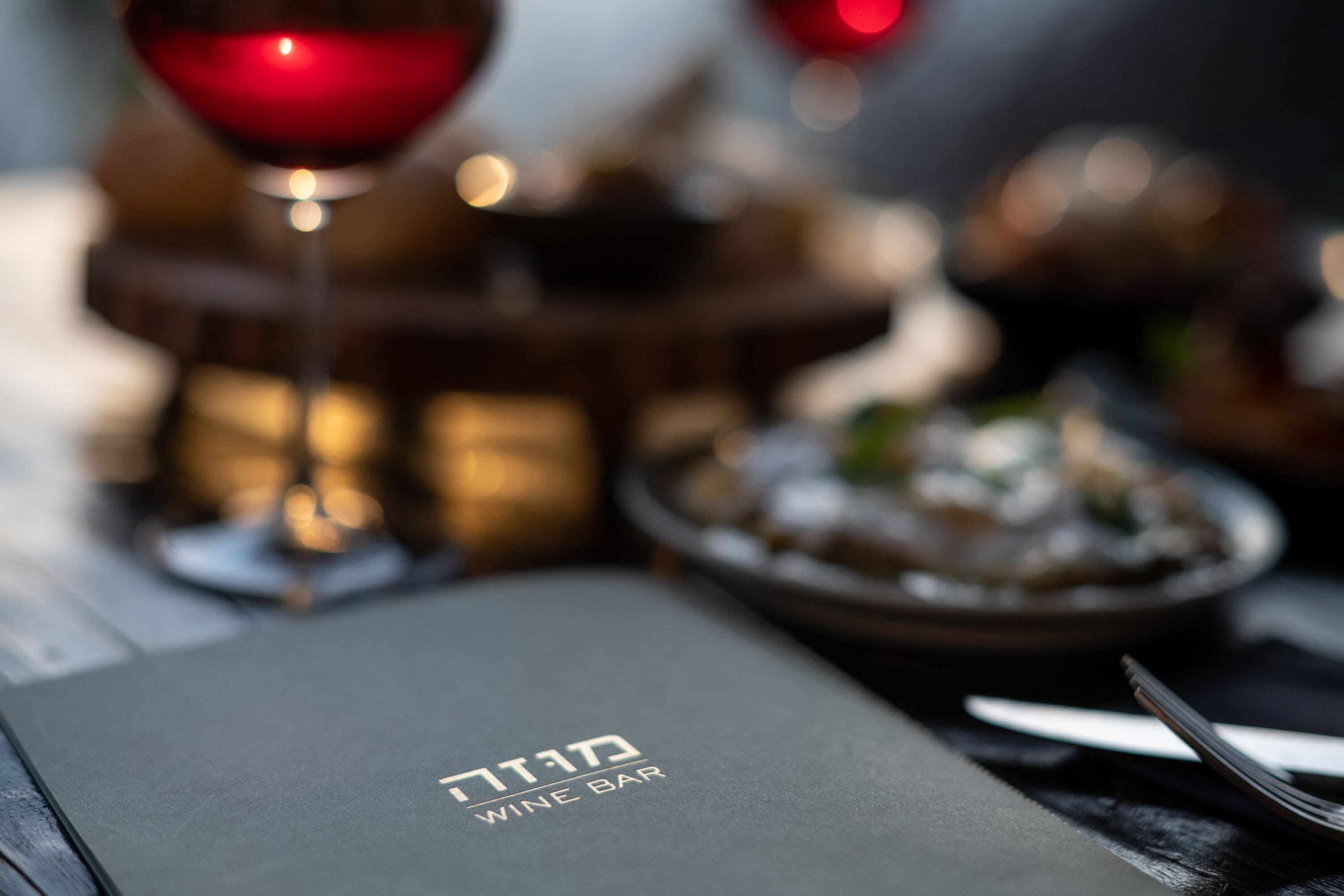A menu with Hebrew text and a wine glass.