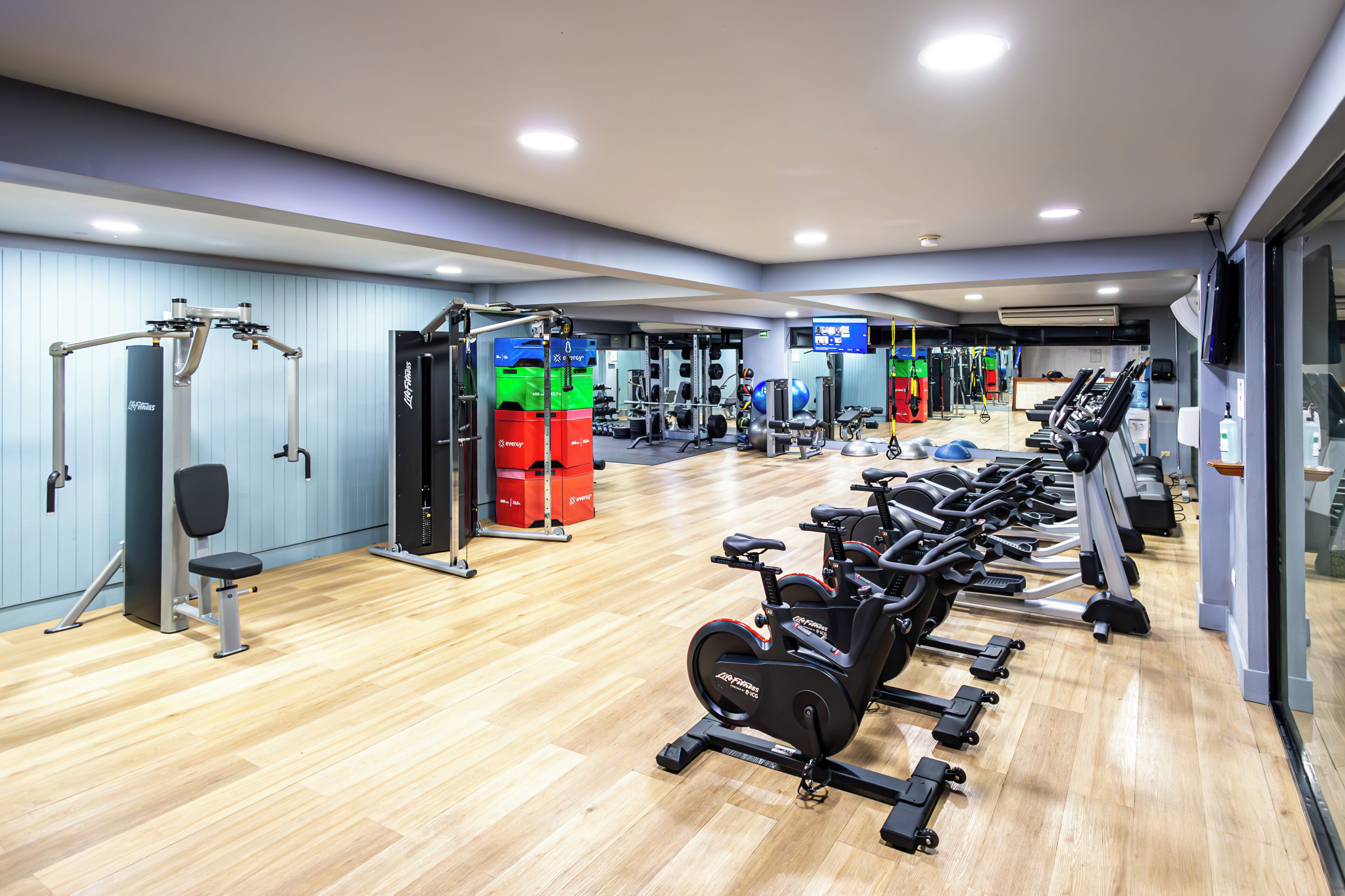 A gym with exercise equipment, a weightlifting area, and a row of stationary bikes.