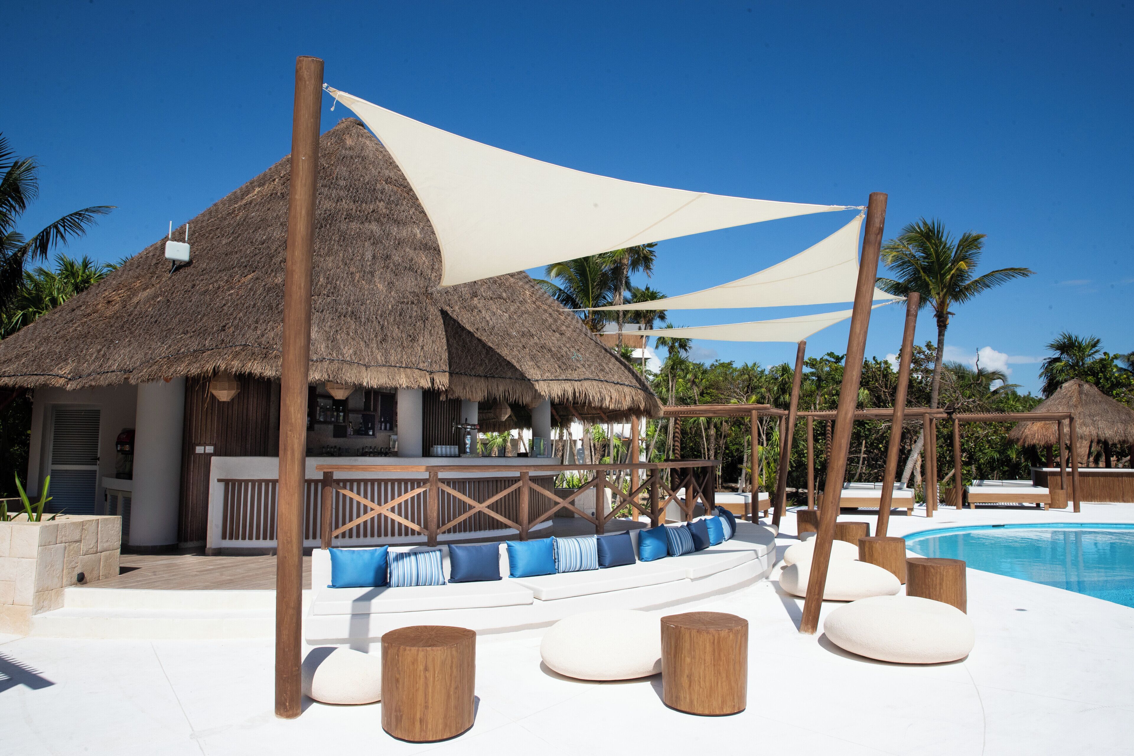 A poolside area with a bar, seating, and thatched-roof structures.