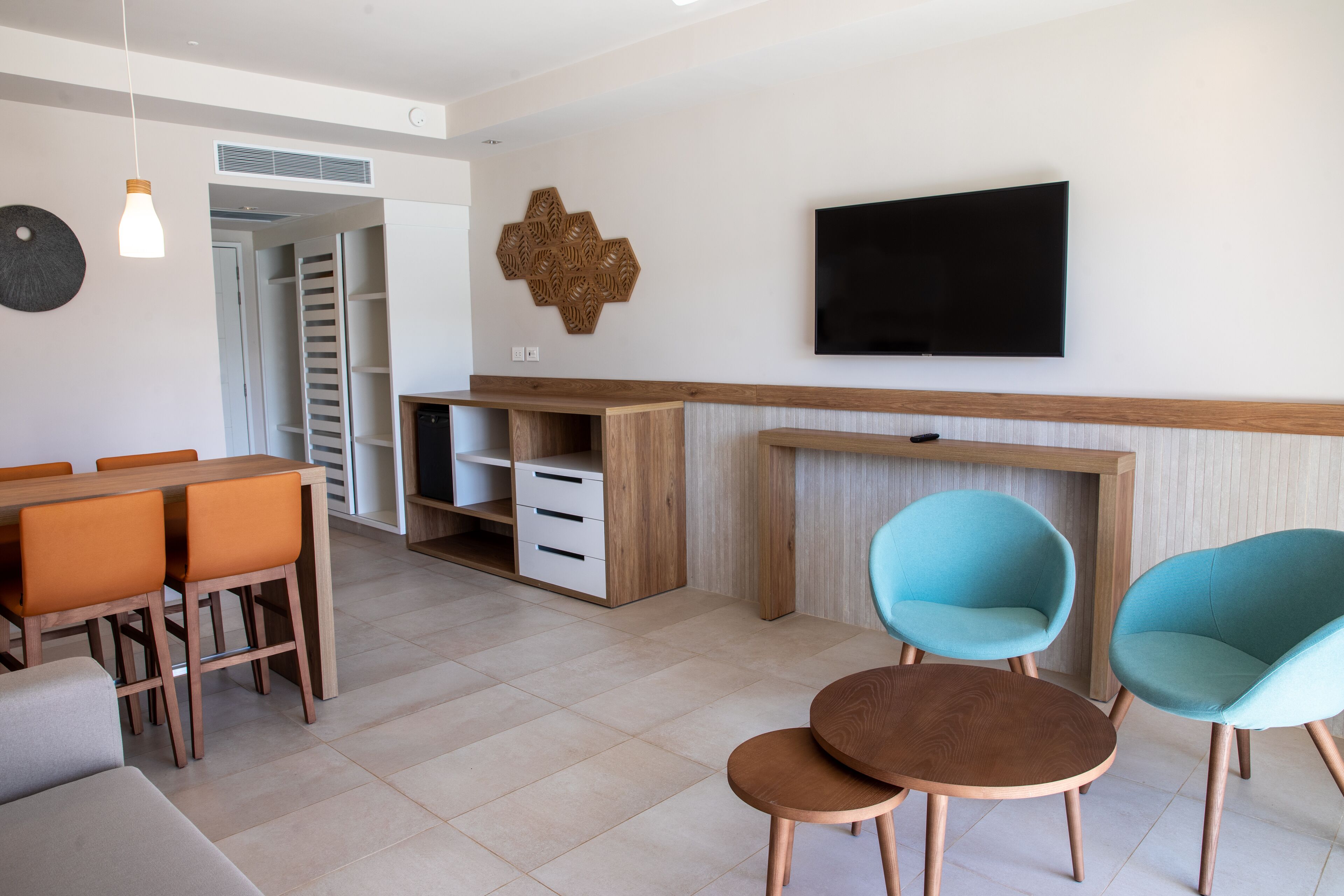 Una sala de estar moderna con comedor, televisor montado en la pared y mueble de madera.