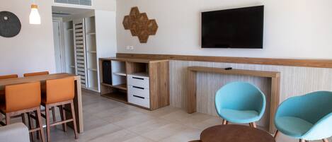 Una sala de estar moderna con comedor, televisor montado en la pared y mueble de madera.