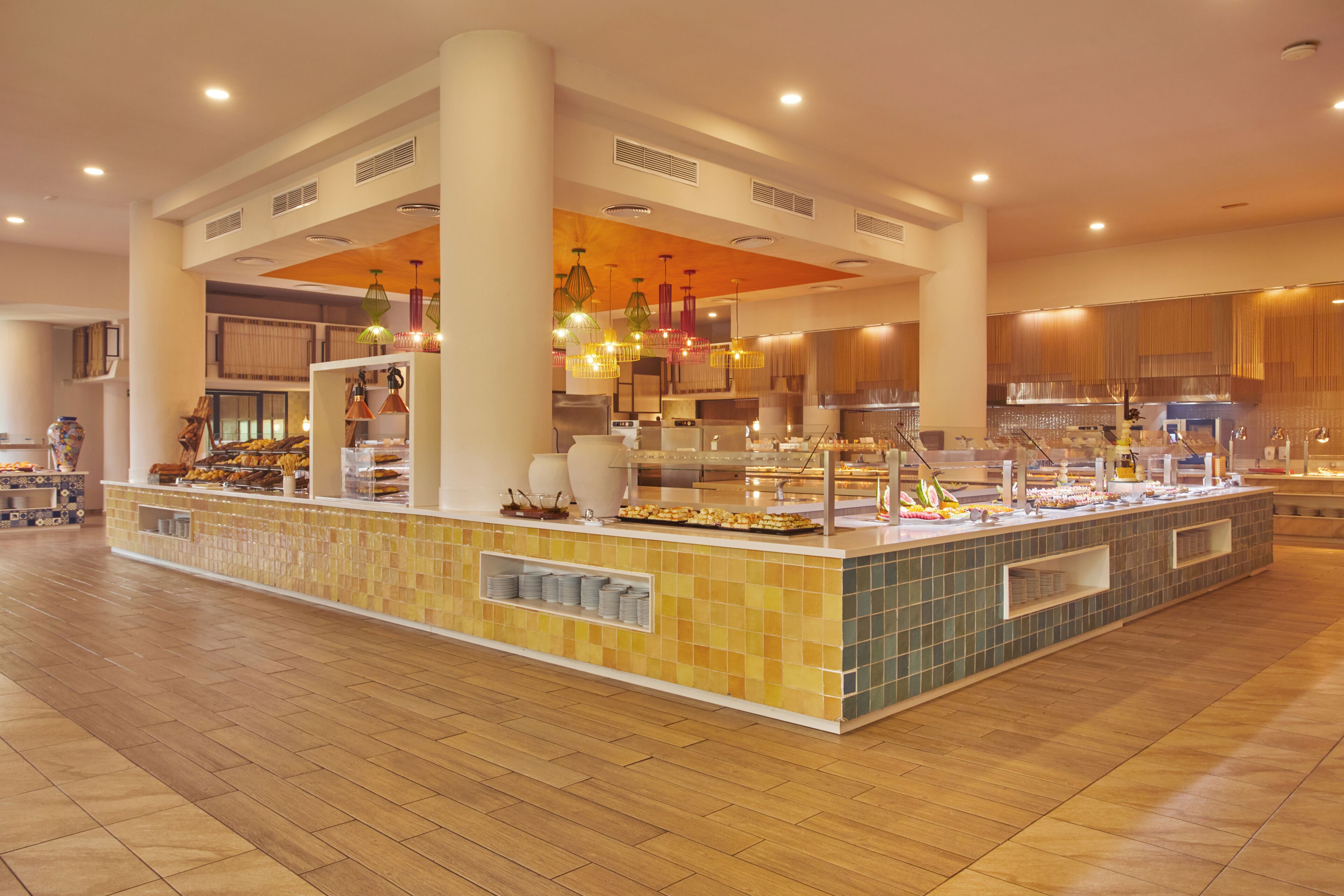 A spacious buffet area with a central island, multiple serving stations, and overhead lighting.