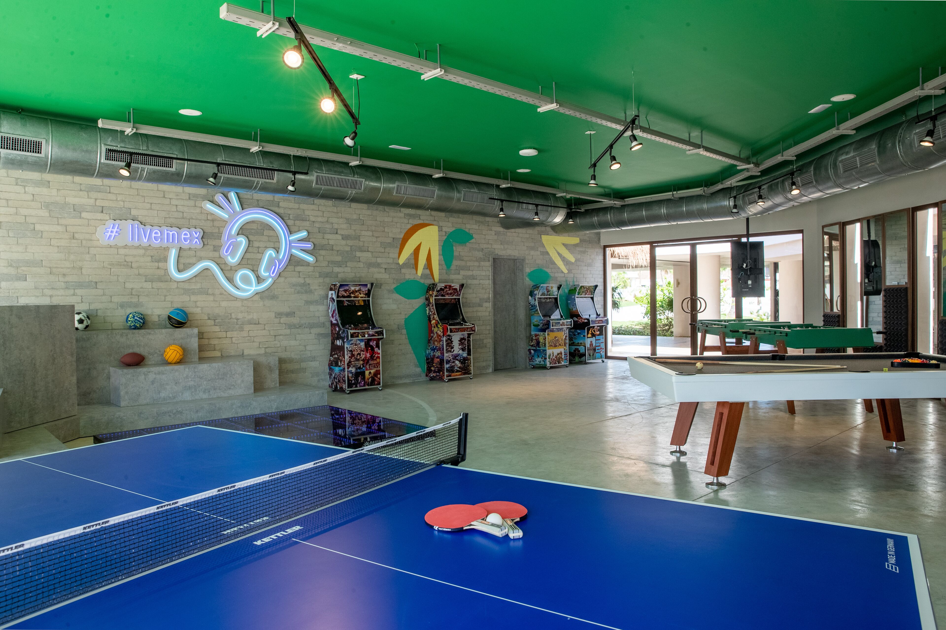 Un espace de loisirs équipé d’une table de ping-pong, d’un billard et de divers équipements sportifs.