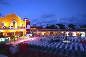 Un espacio para eventos con un escenario y filas de sillas, con la leyenda "VIVA MEXICO", lo que sugiere un lugar para una presentación o espectáculo.
