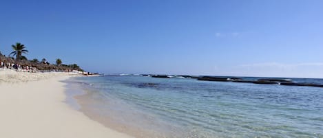 Playa privada, arena blanca, sombrillas y toallas de playa