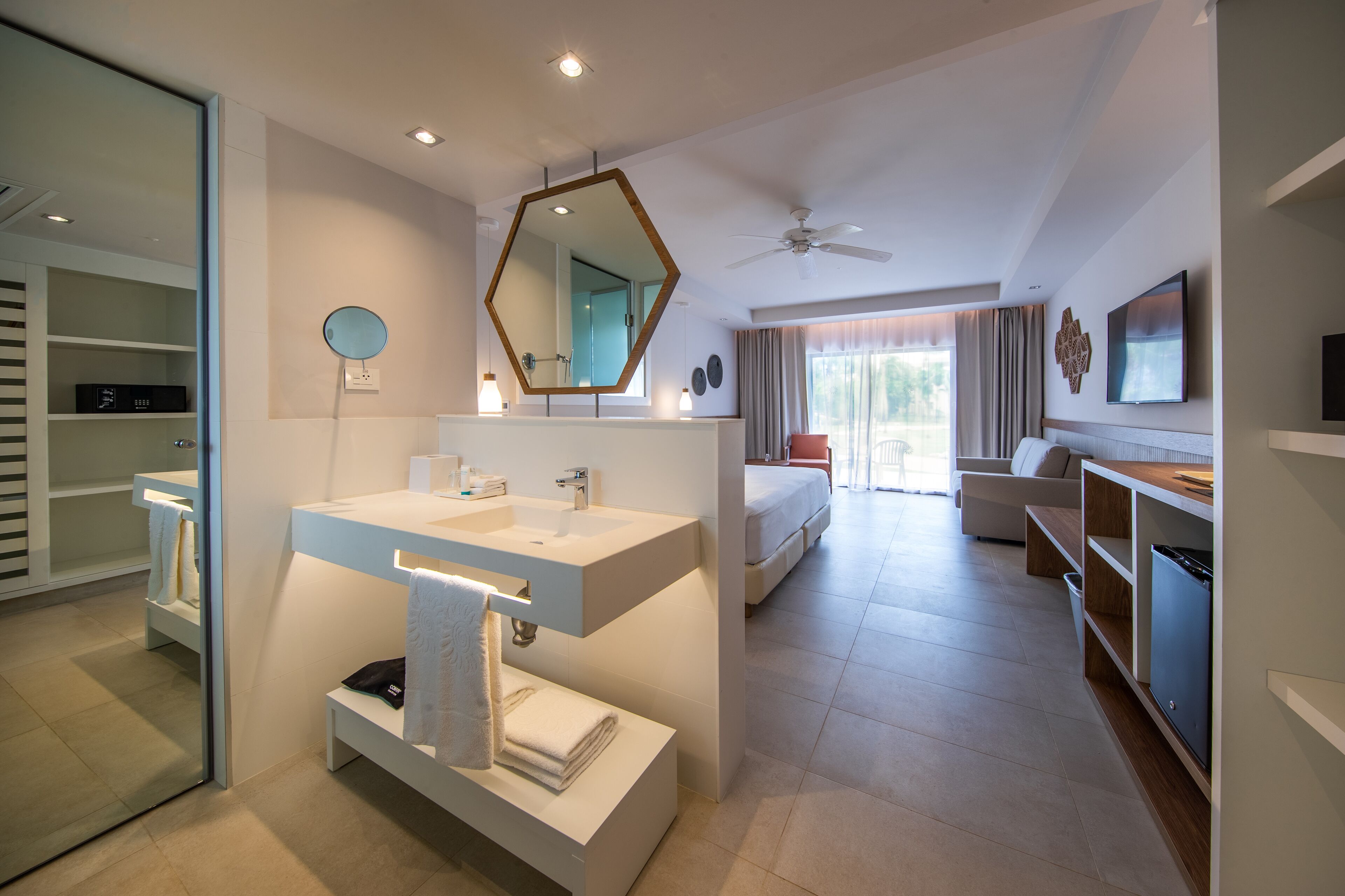 A modern hotel bathroom with a large mirror, a sink, and a vanity.