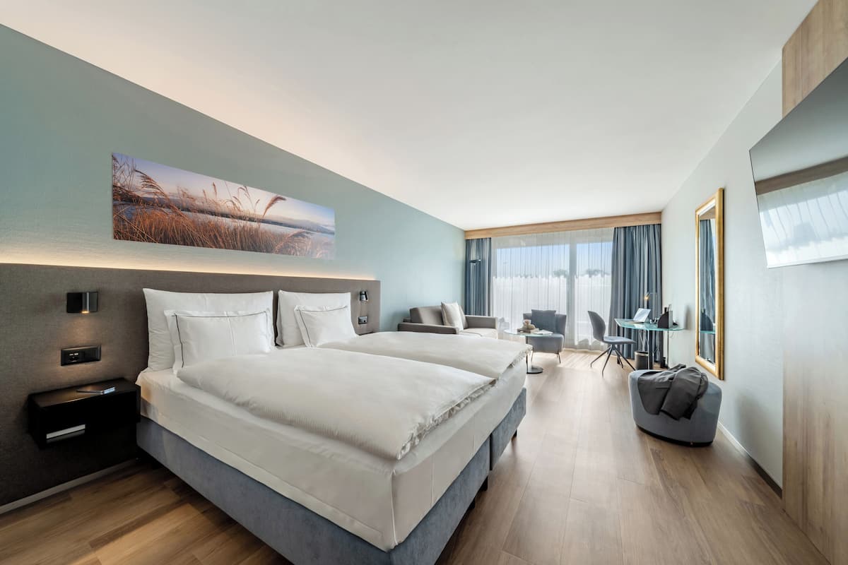 Una habitación de hotel moderna con una cama grande, mesitas de noche, un escritorio y una silla.