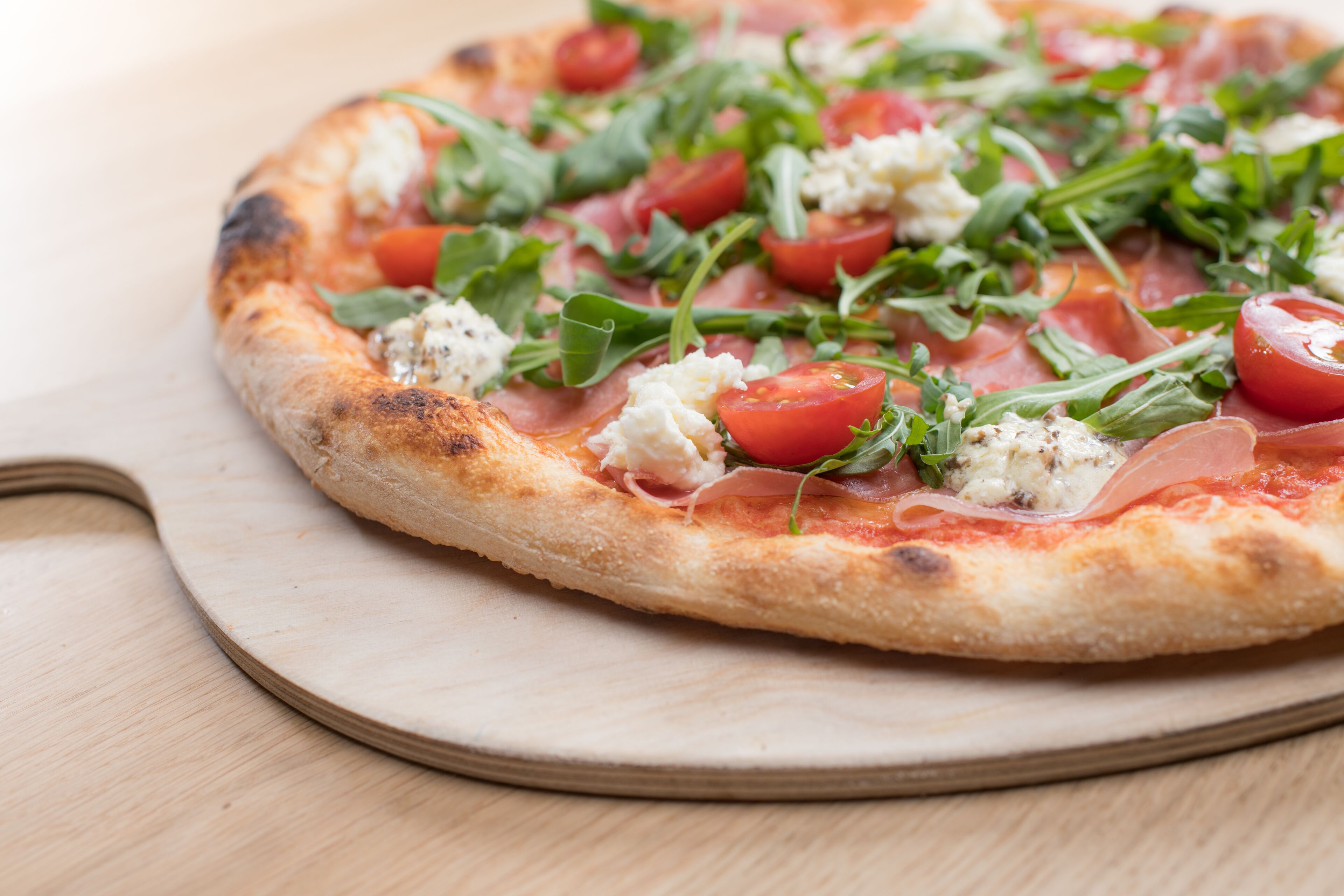 Eine Pizza mit Belag auf einer Holzbrett.