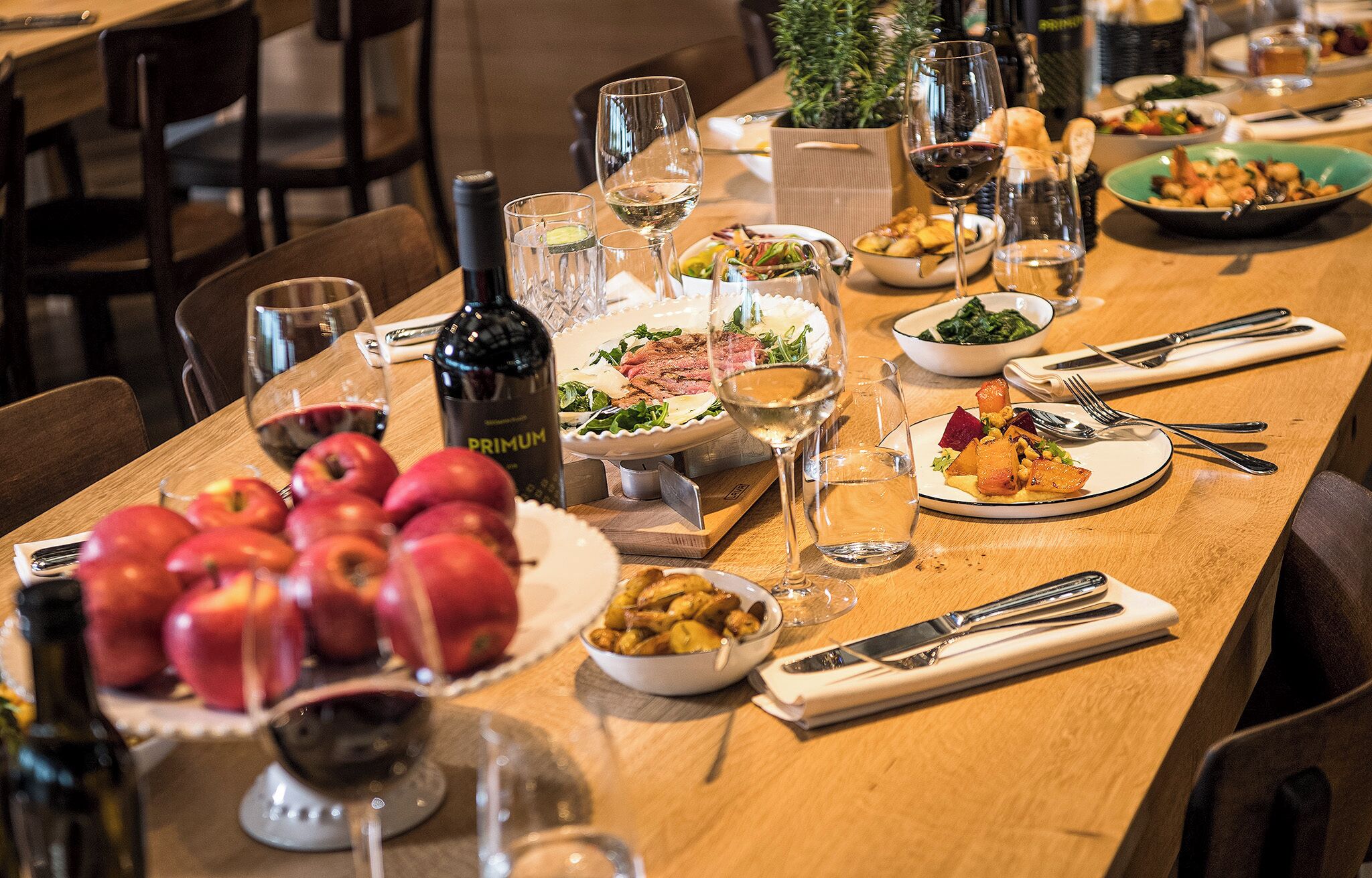 Une table à manger dressée avec différents plats, des verres à vin et une bouteille de vin.