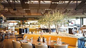A restaurant with tables set for dining, a bar area, and a counter with a menu.