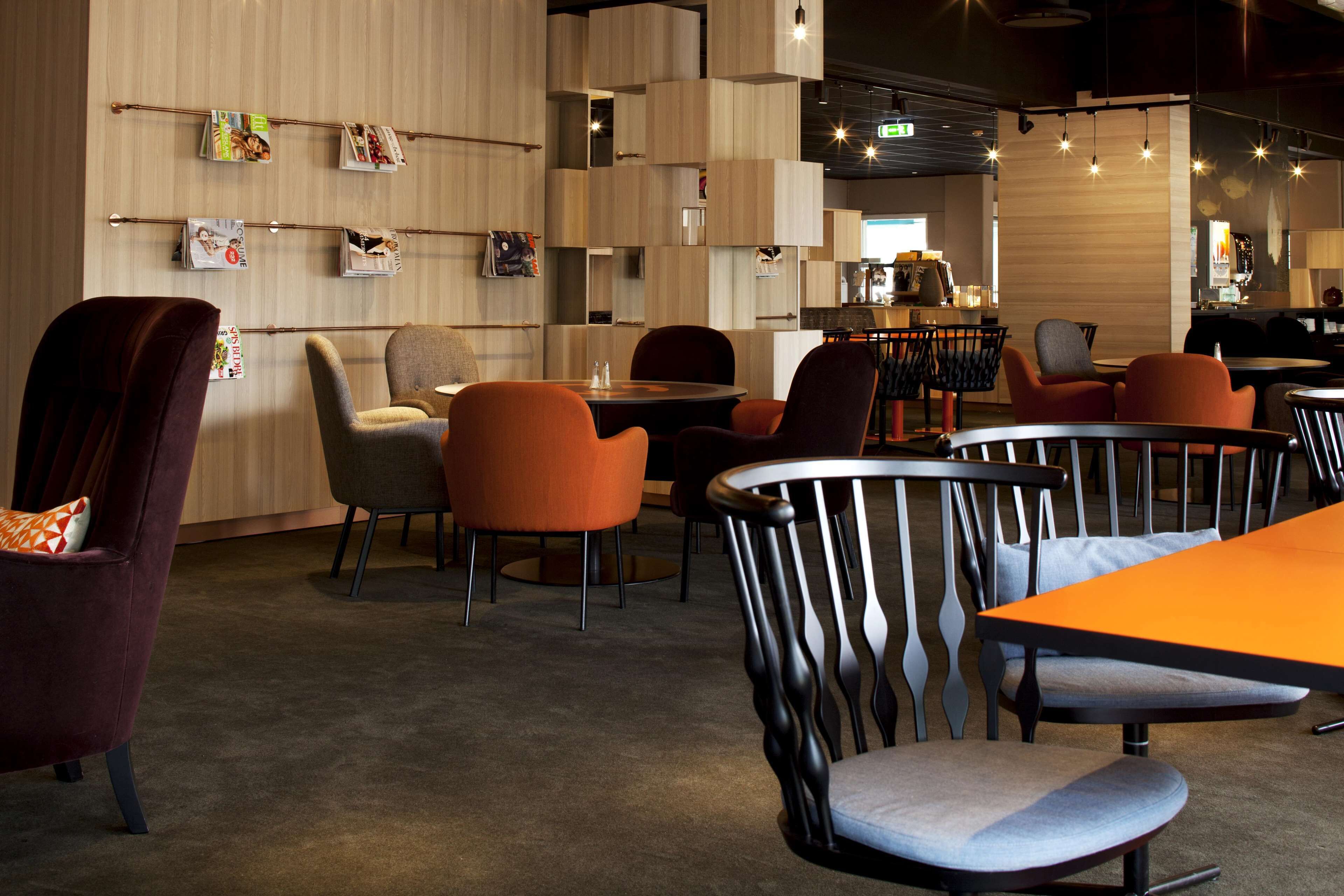 A modern restaurant interior with wooden panel walls, multiple seating areas, and a bar counter.