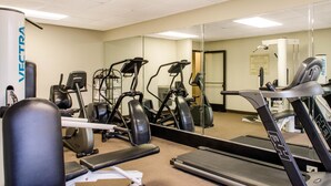 Ein Fitnessstudio mit verschiedenen Trainingsgeräten, darunter Laufbänder und Crosstrainer.